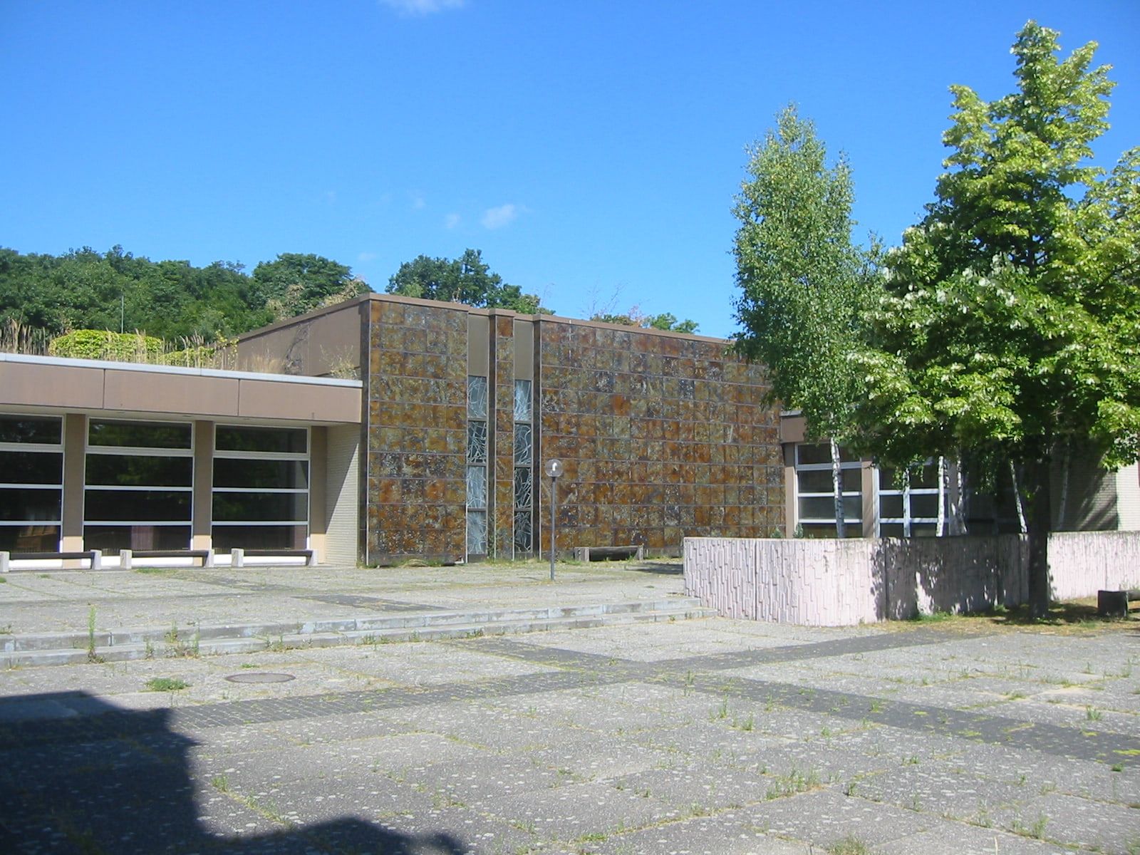 Mourning hall with a natural-stone facade and broad window frontage at Gatow Landscape Cemetery